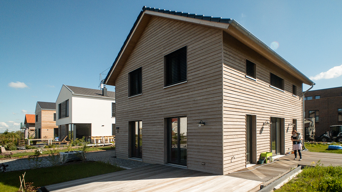 04_Kleines_Einfamilienhaus_Holzhaus_Holzrahmenbau_Silbergraue_Holzfassade_Waagerecht_im_Neubaugebiet