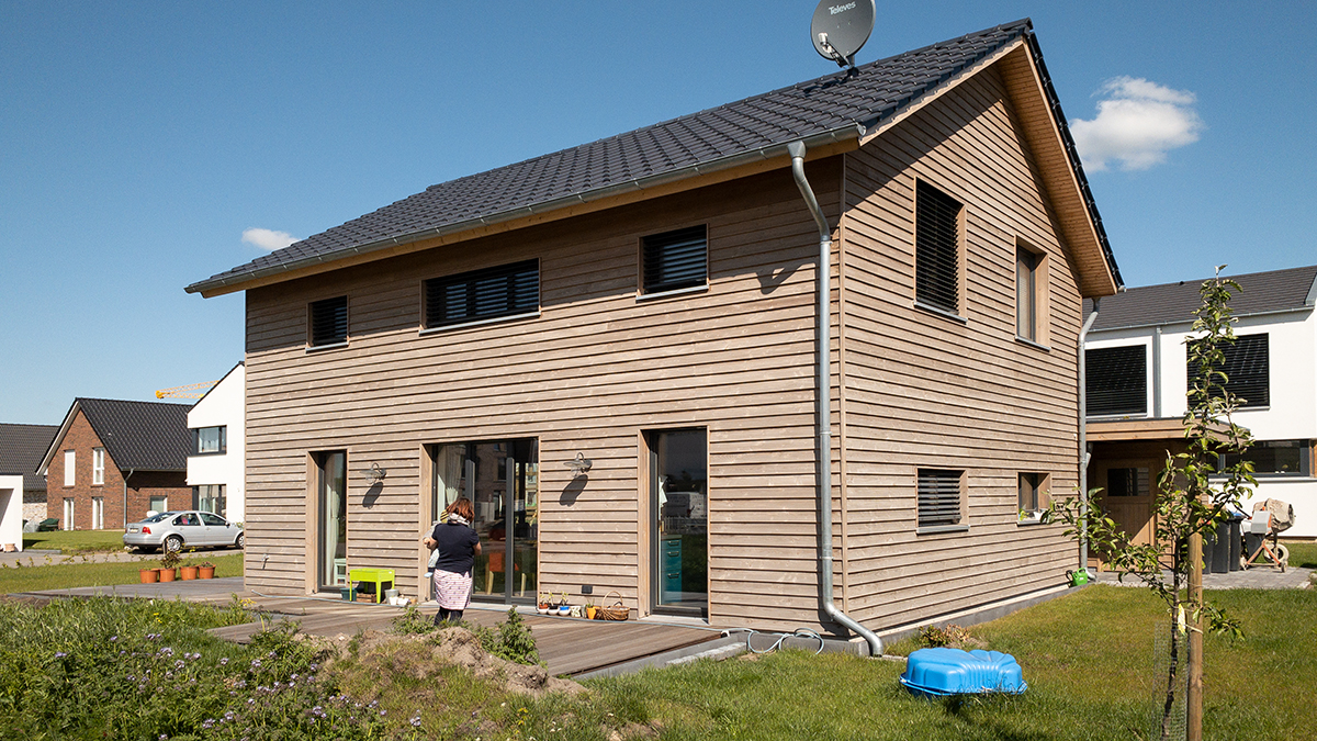 05_Kleines_Einfamilienhaus_Holzhaus_Holzrahmenbau_Silbergraue_Holzfassade_Waagerecht_im_Neubaugebiet