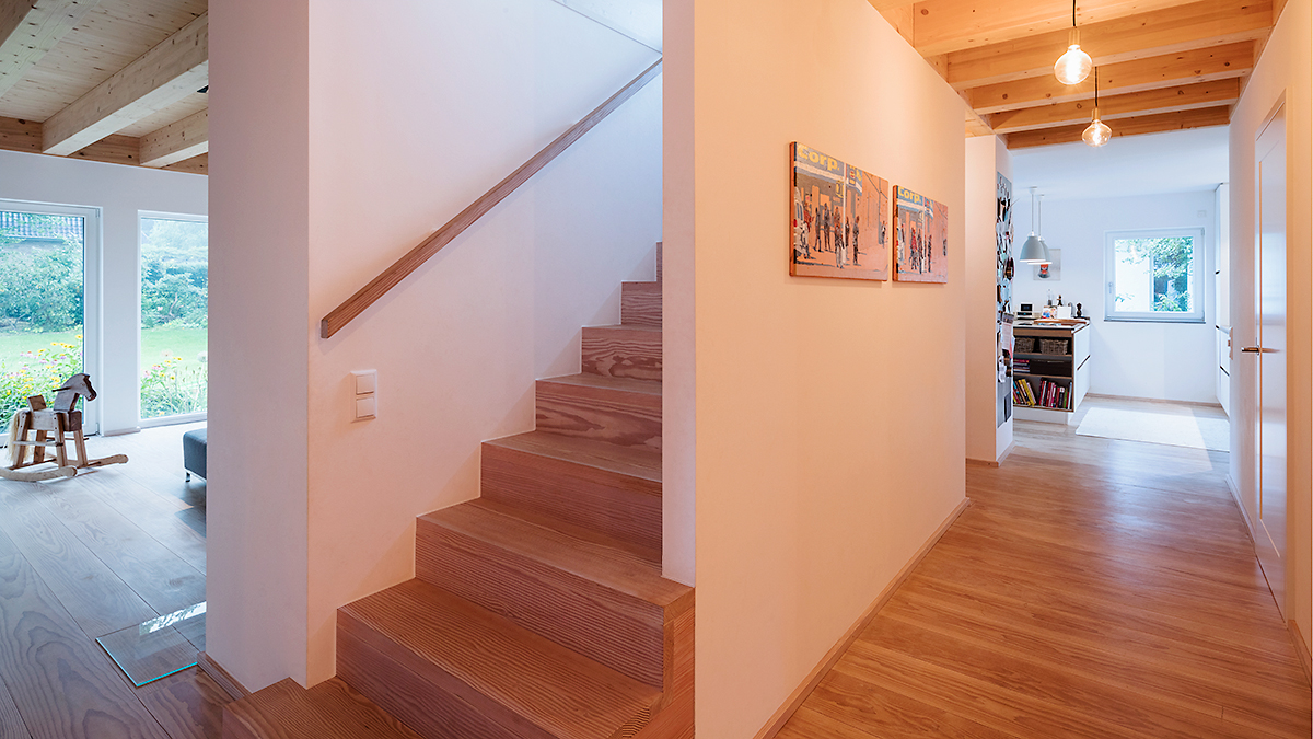 08_Modernes_Holzhaus_fuer_Zwei_Familien_Doppelhaus_Treppe_als_Raumtrenner_Holztreppe_Heller_Flur