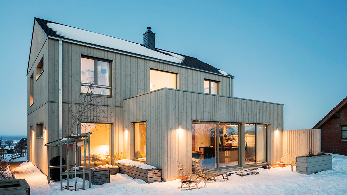 03_Modernes_Grundofenhaus_Holzhaus_ohne_Dachueberstand_Winter_Senkrechte_Holzfassade