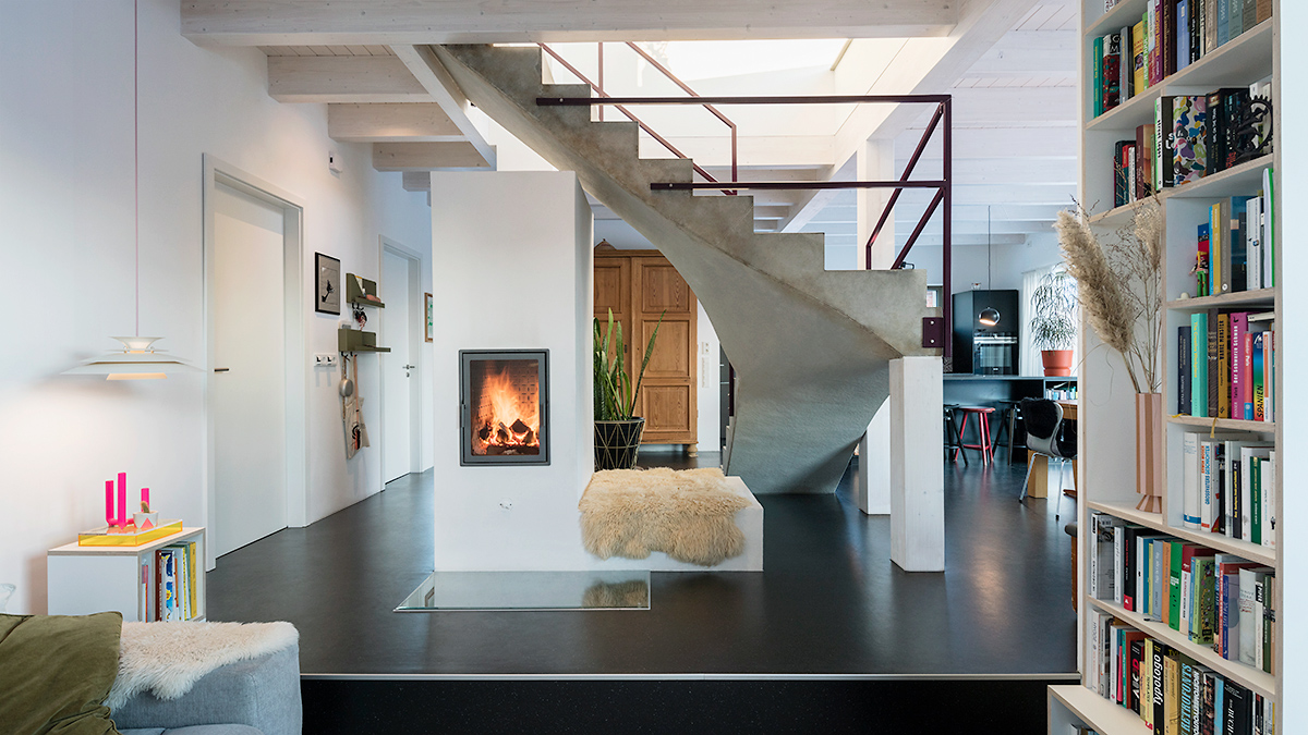 09_Grundofenheizung_als_Herzstueck_des_Hauses_Ofen_Unter_Treppe_offener_moderner_Grundriss_Holzhaus